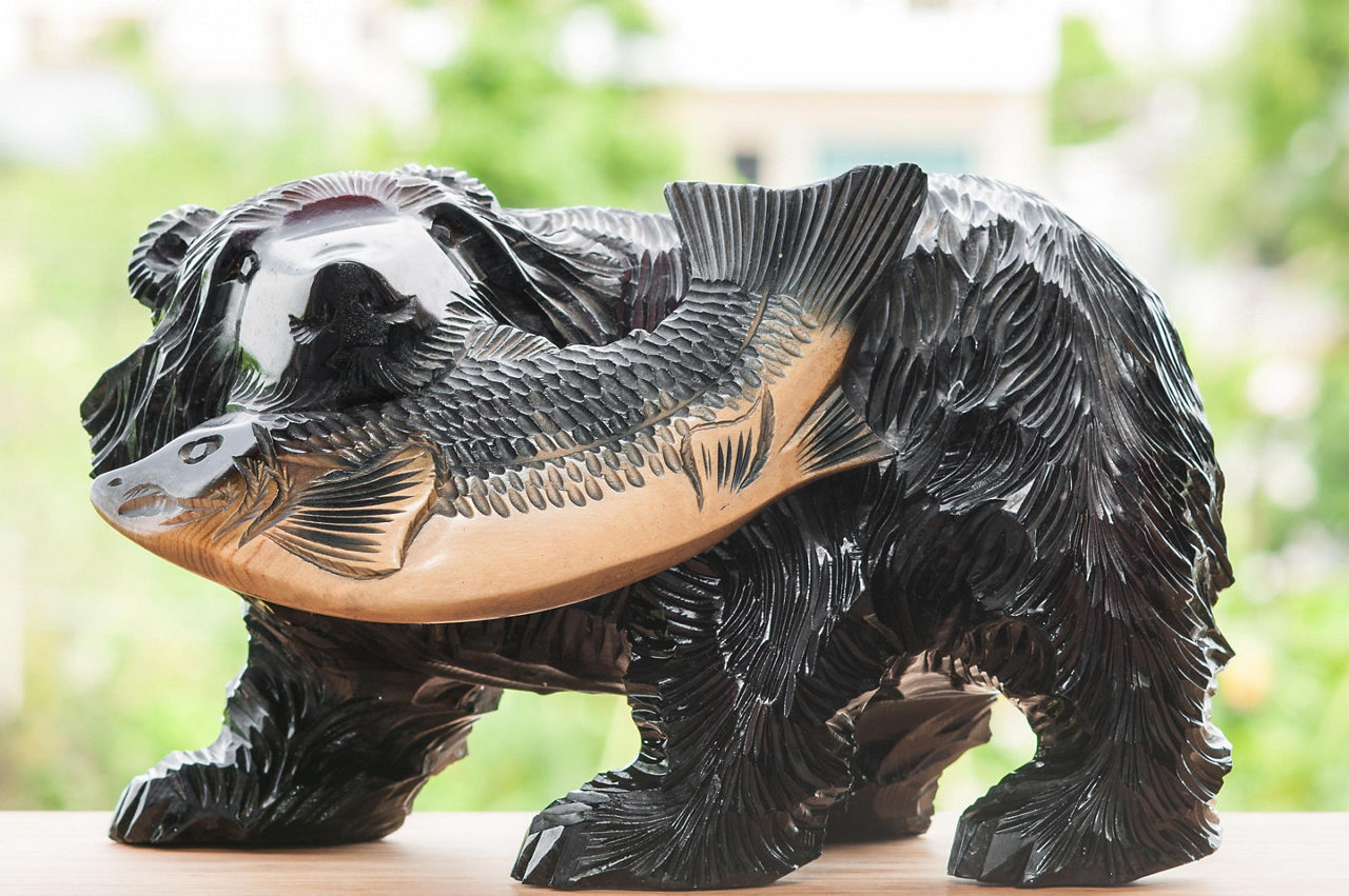 A tradiitonal Hokkaido wood carving of a bear with a salmon in its mouth
