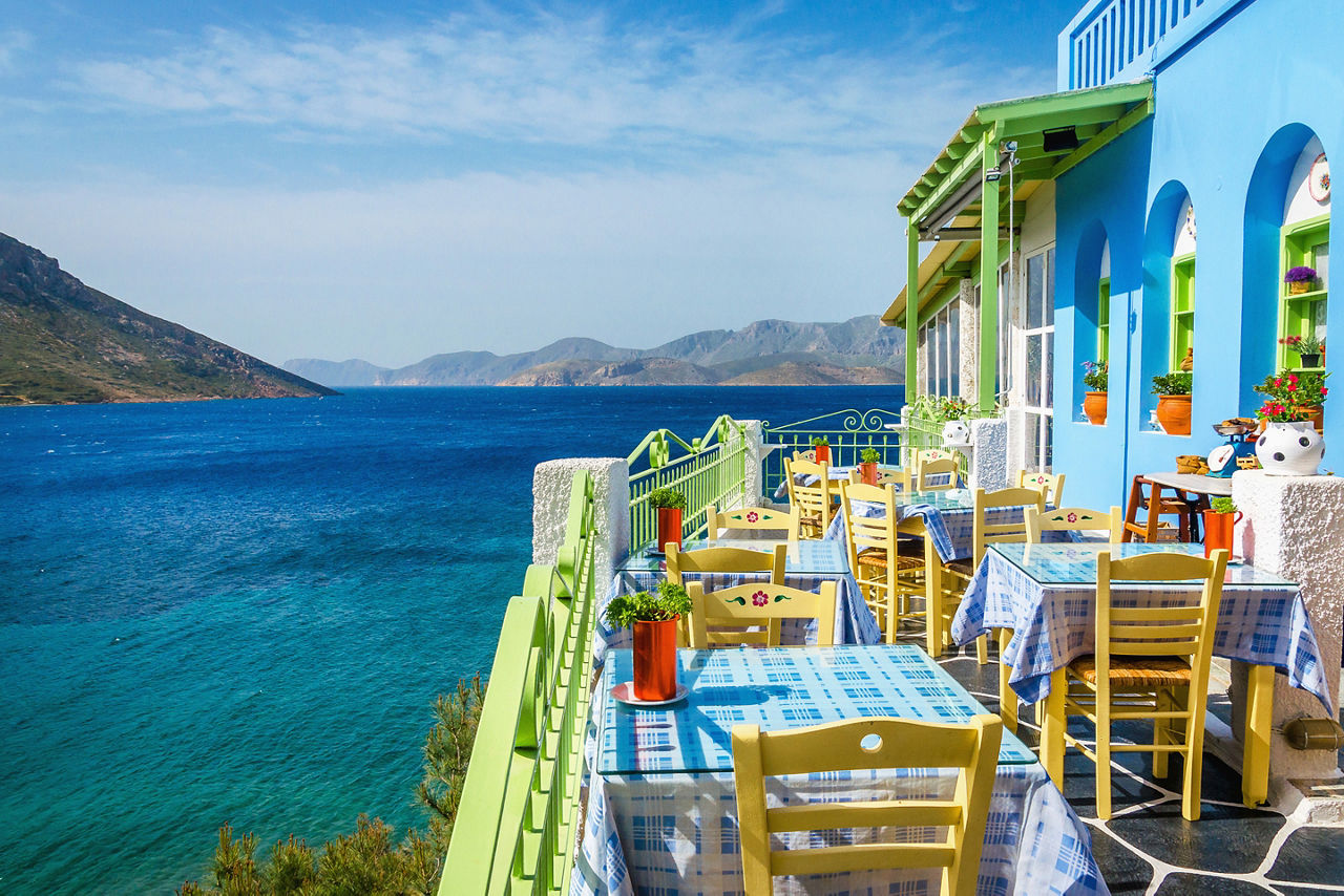 Typical Greek restaurant on the balcony blue building overlooking the sea, Greece