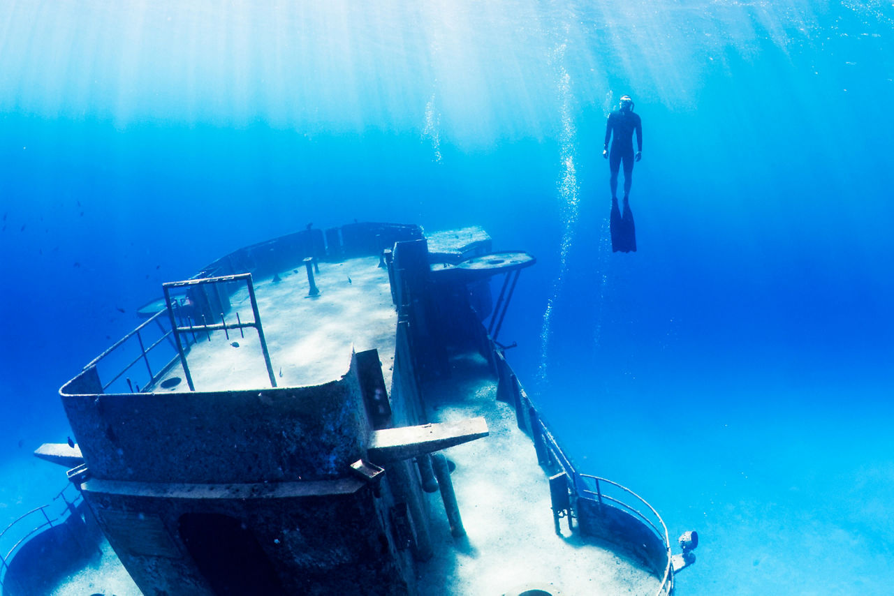 Free diver swimming up from a large underwater shipwreck. The Caribbean.