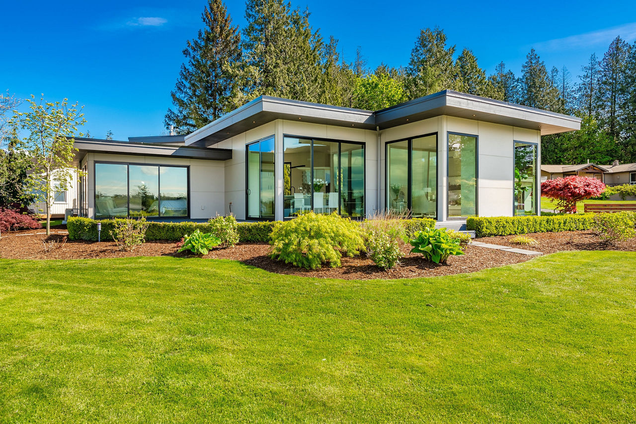 Contemporary home exterior on lakeshore with flat roof and large feature windows