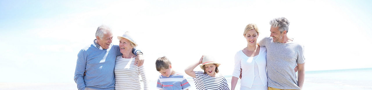 Family, parents, grandparents and grandkids walking on the beach