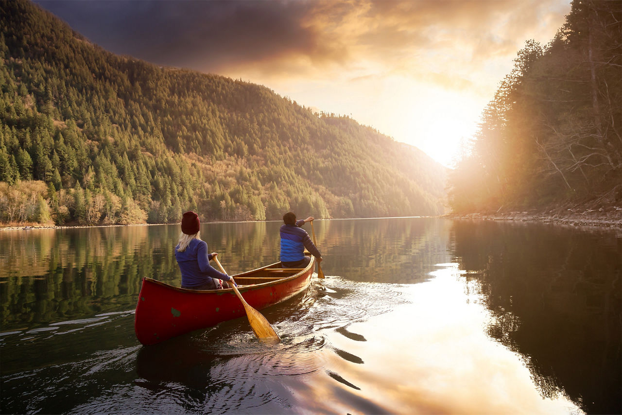 romantic couple canoeing toward a vacation sunset. Canada.