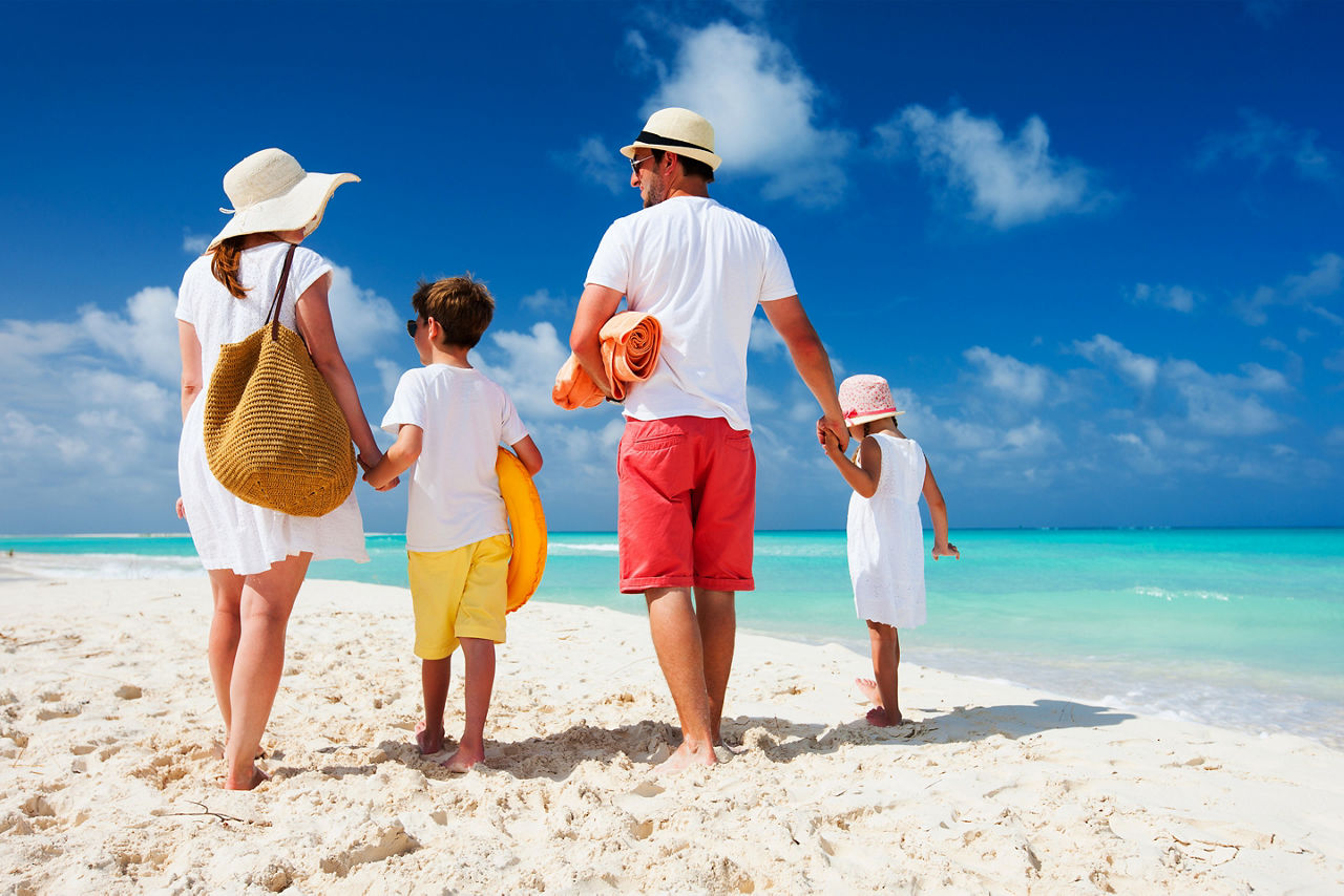 Family of four on a tropical summer beach getaway vacation. The Caribbean.