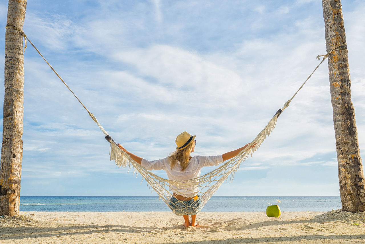 Female teacher reading a book in a hammock while on summer vacation. North America