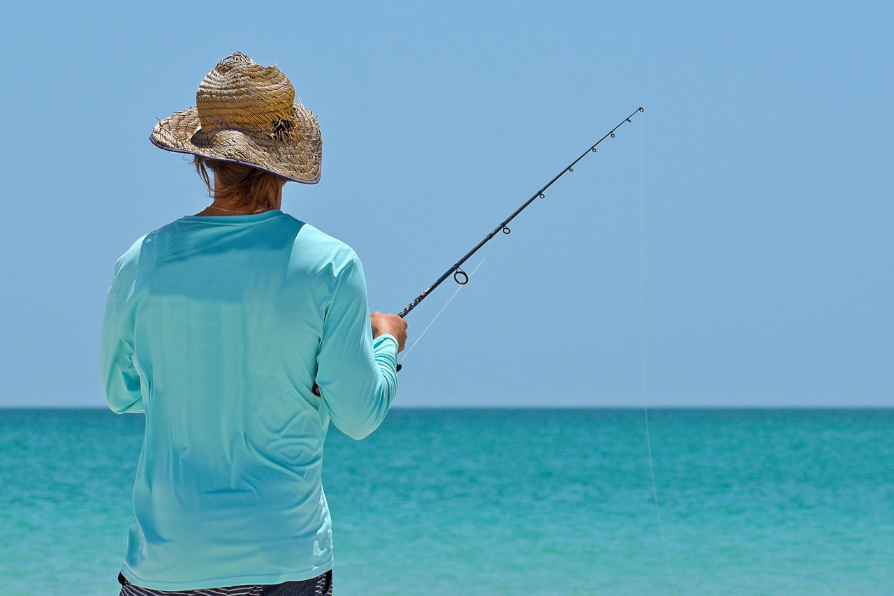 An unidentified local young man on the beach fishing in the shallow water of the Gulf of Mexico.  