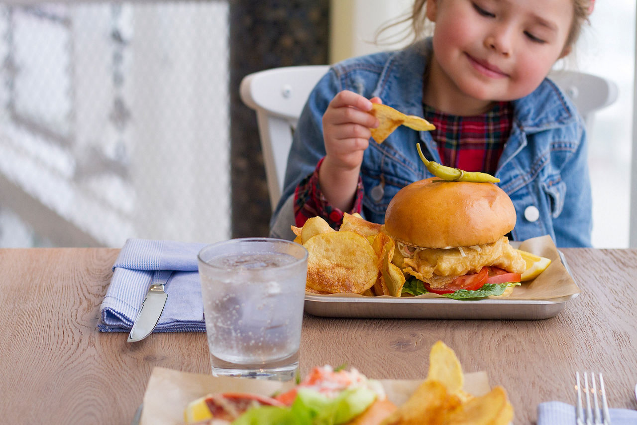 Little Girl Enjoying Fish Sandwich with Chips