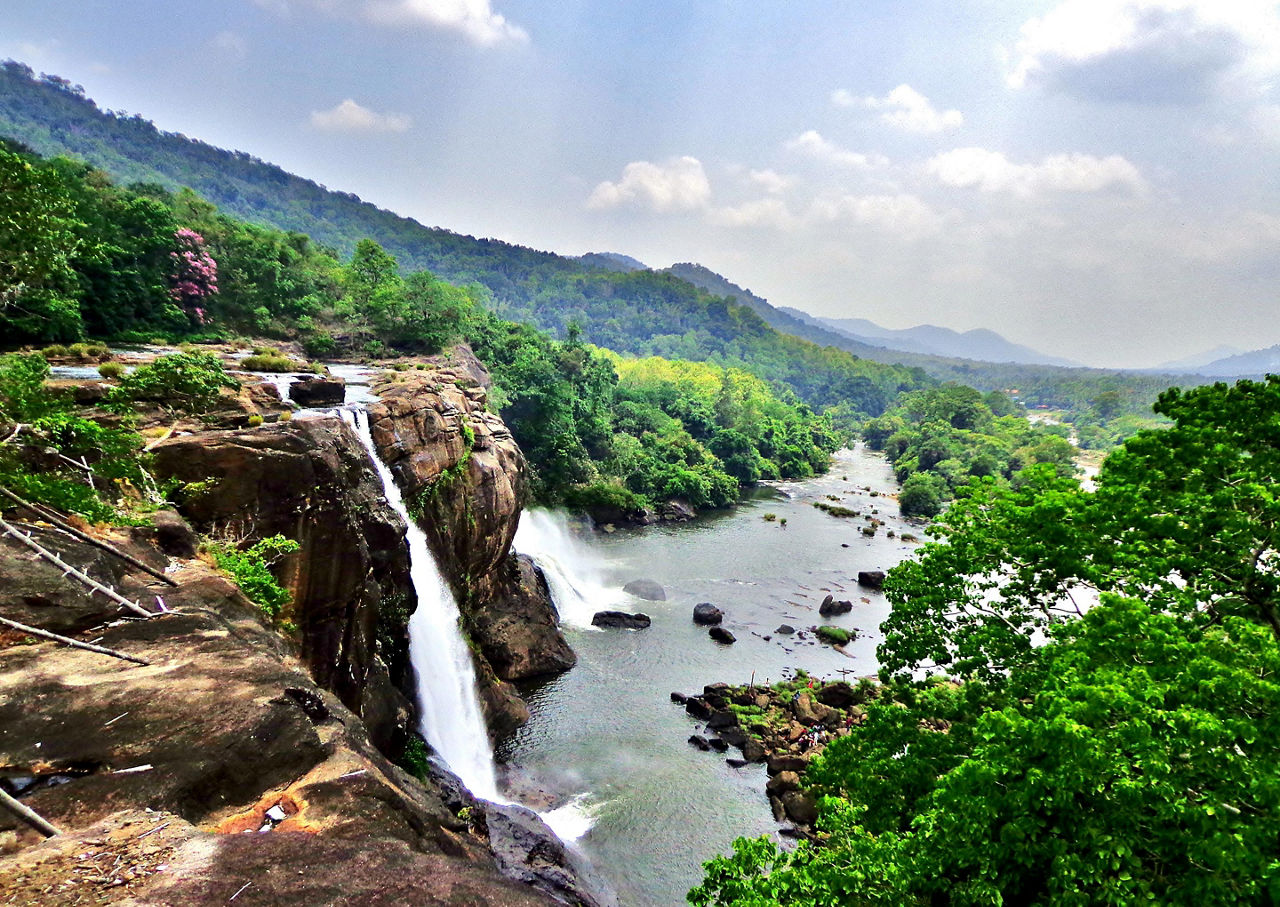 At the edge of the Athirapally Waterfall in Kerala, with a stunning view of the surrounding jungle and mountains in Cochin, India