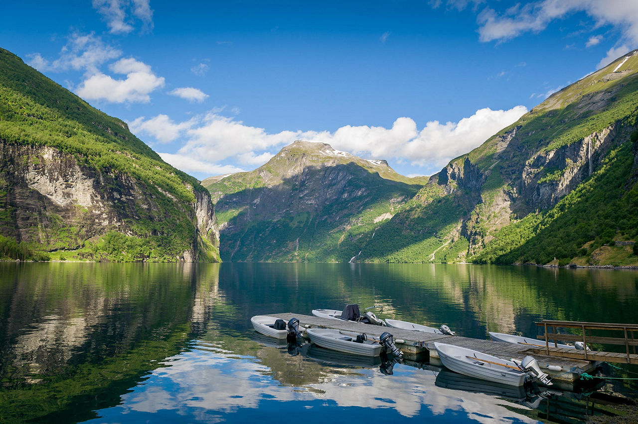 Multiple small boats docked at a pier in Geiranger, Norway,