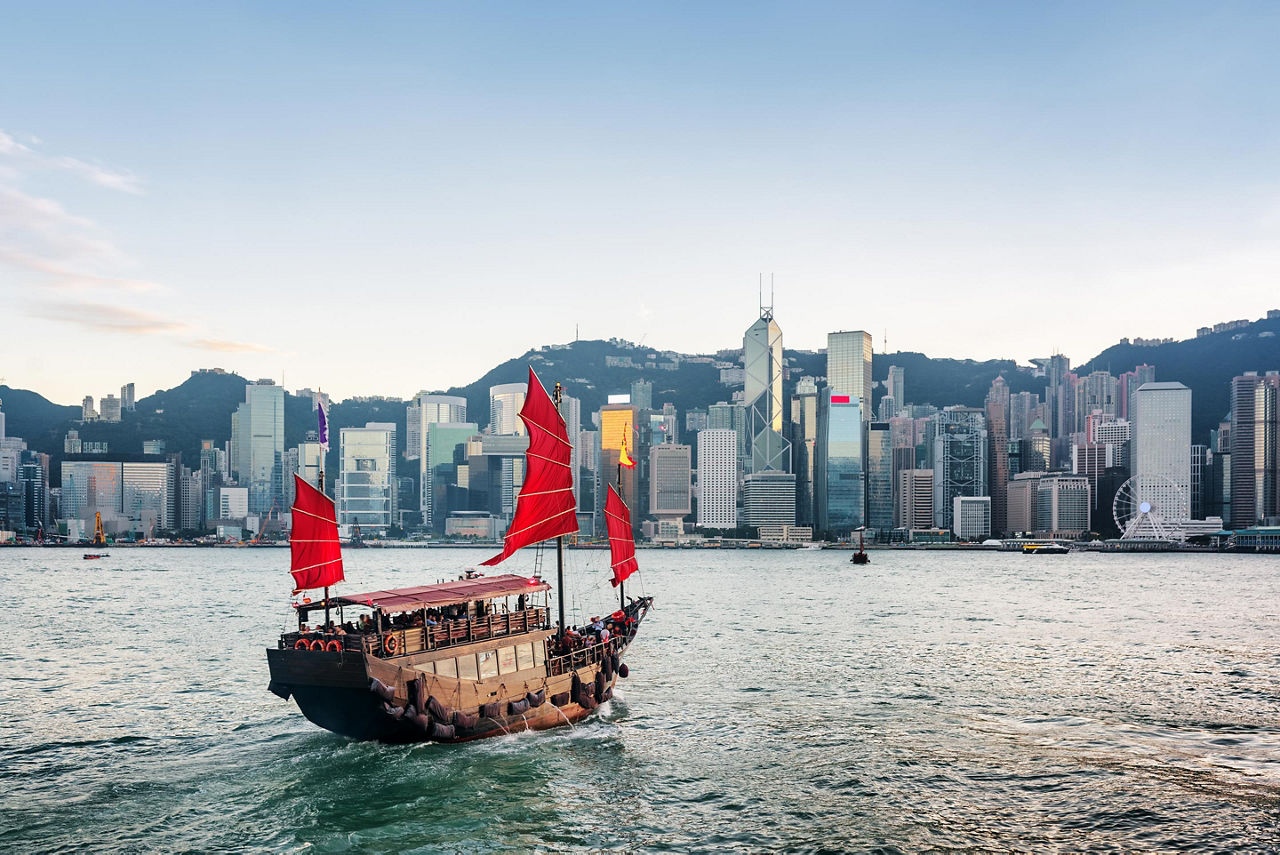 Tourist sailboat crosses Victoria Harbour to the Hong Kong Island with skyscrapers in the background