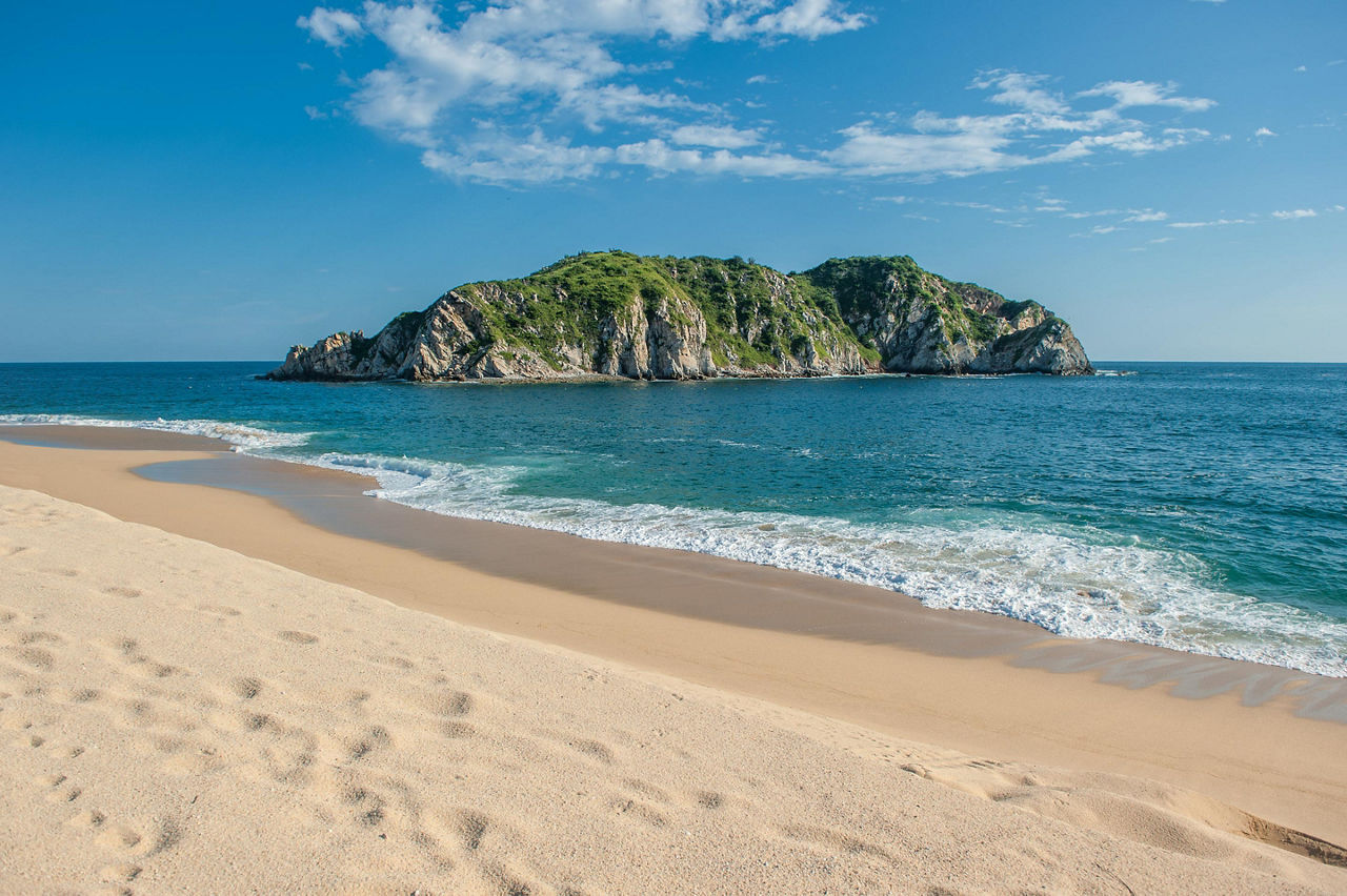 A big rock coming out of the ocean on the Cacaluta Beach in Huatulco, Mexico 