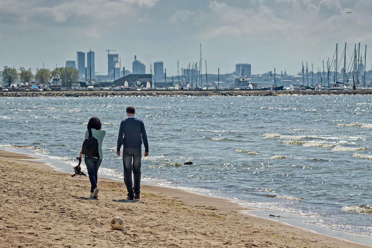 A man and a woman walking on a beach in Tallinn, Estonia