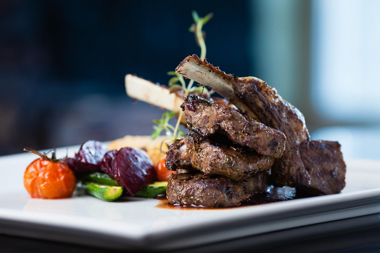 Grilled lamb on a white plate with roasted vegetables