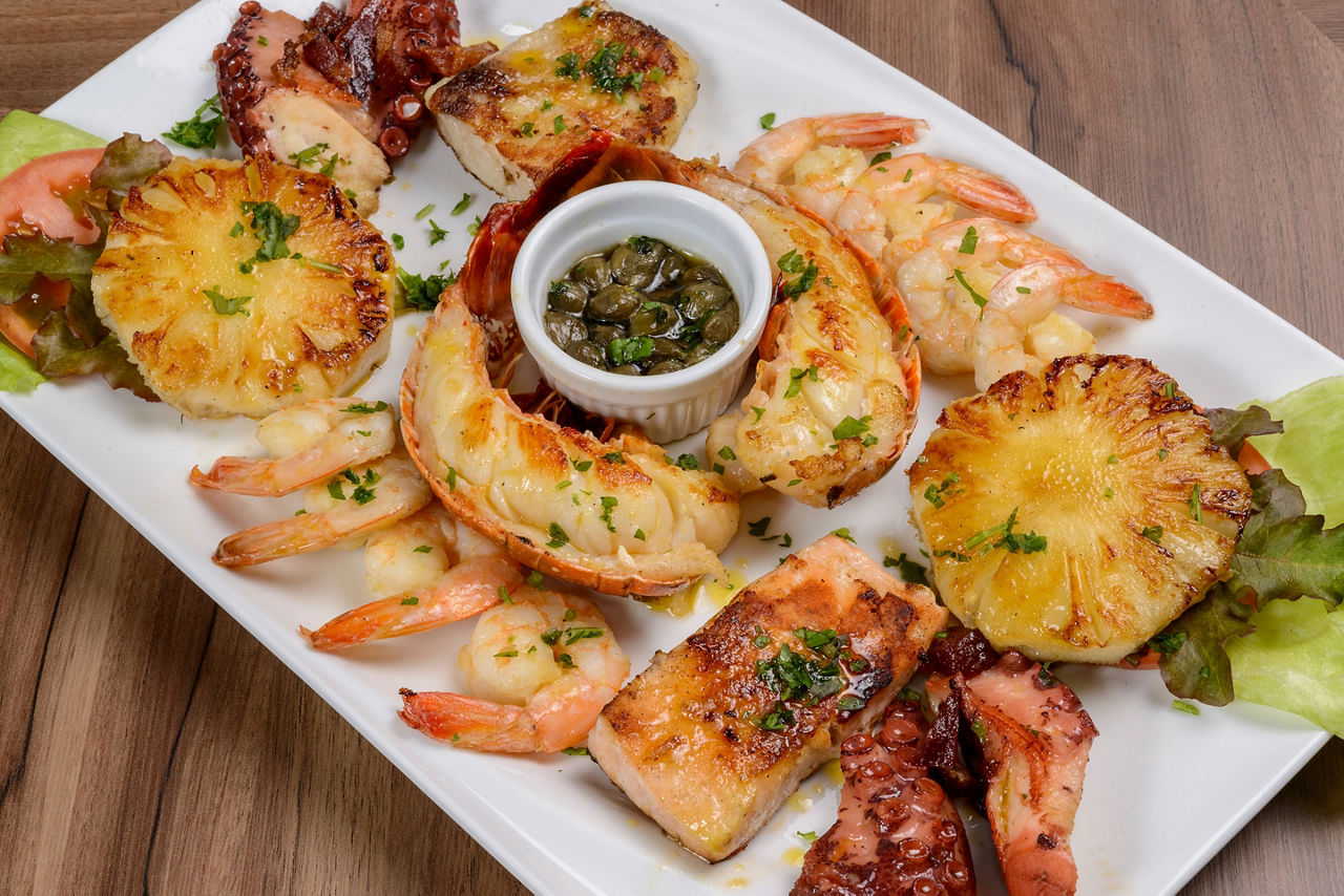 Seafood. Lobster, shrimp, octopus and fish in white bowl on wooden table. Brazilian food.